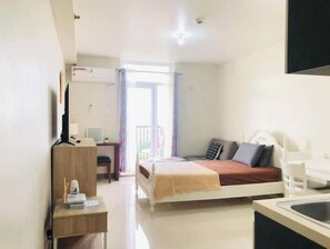 Cozy retreat with a single bed, desk area, and large window offering a view of the outside balcony.