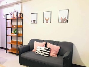 Relax in a comfortable living space with a sofa, decorative pillows, and a wooden shelving unit.