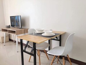 Enjoy meals in this cozy dining area with a table for two, a TV for entertainment, and a clean, minimalist layout.