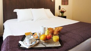 A hotel room with a neatly made bed, a tray with breakfast items, and a vase with flowers on the nightstand. - Savoy Hotel (Brides-les-Bains)