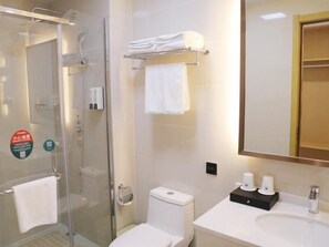 A modern bathroom with a glass shower enclosure, a toilet, a sink with a mirror, and a towel rack.