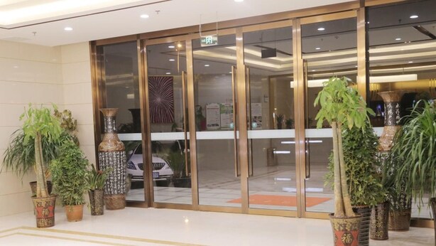 A hotel entrance with a glass door, potted plants, and a tiled floor. - Greentree Inn Hefei Feidong County High Speed Rail Station Wuyue Plaza Express Hotel (Hefei)