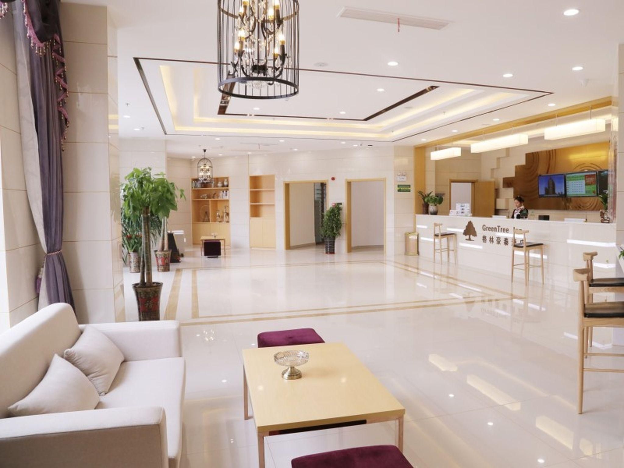 A hotel lobby with a reception desk, seating area, and a chandelier.