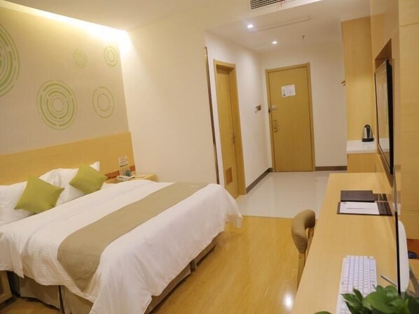 A hotel room with a bed, a desk, and a chair. There is a door leading to another room and a wall with circular patterns.