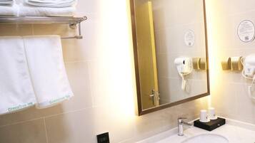 A hotel bathroom with a sink, towel rack, and two hair dryers.