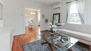 Uma sala de estar moderna com uma mesa de centro de vidro, um sofá e uma área de jantar com cadeiras.
