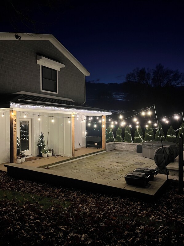 A house with a covered patio area, string lights, and a small Christmas tree. - 2-bedroom house with Hot tub & Pool- Near Douglas & Saugatuck (Fennville)