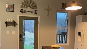 A kitchen with a wooden table, a white refrigerator, and a door leading to a backyard.