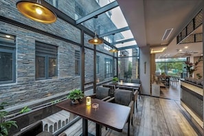 A restaurant with a stone wall, wooden flooring, and hanging pendant lights.
