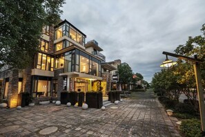 Un immeuble moderne à plusieurs étages, doté de grandes fenêtres et d’une cour dallée.