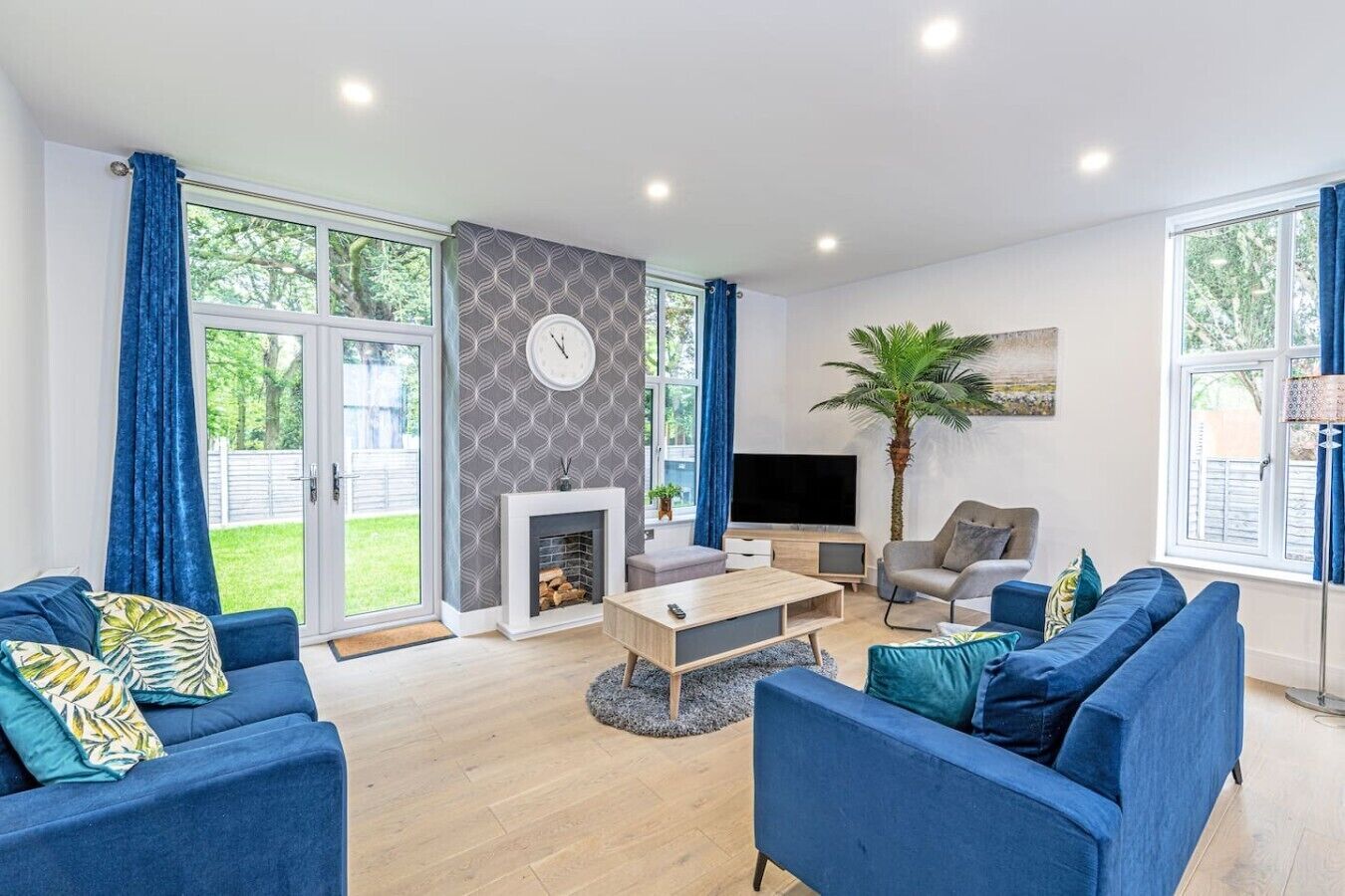 A modern living room with a fireplace, a television, and a large window with curtains.