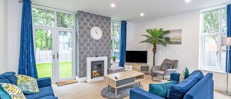 A modern living room with a fireplace, a television, and a large window with curtains.