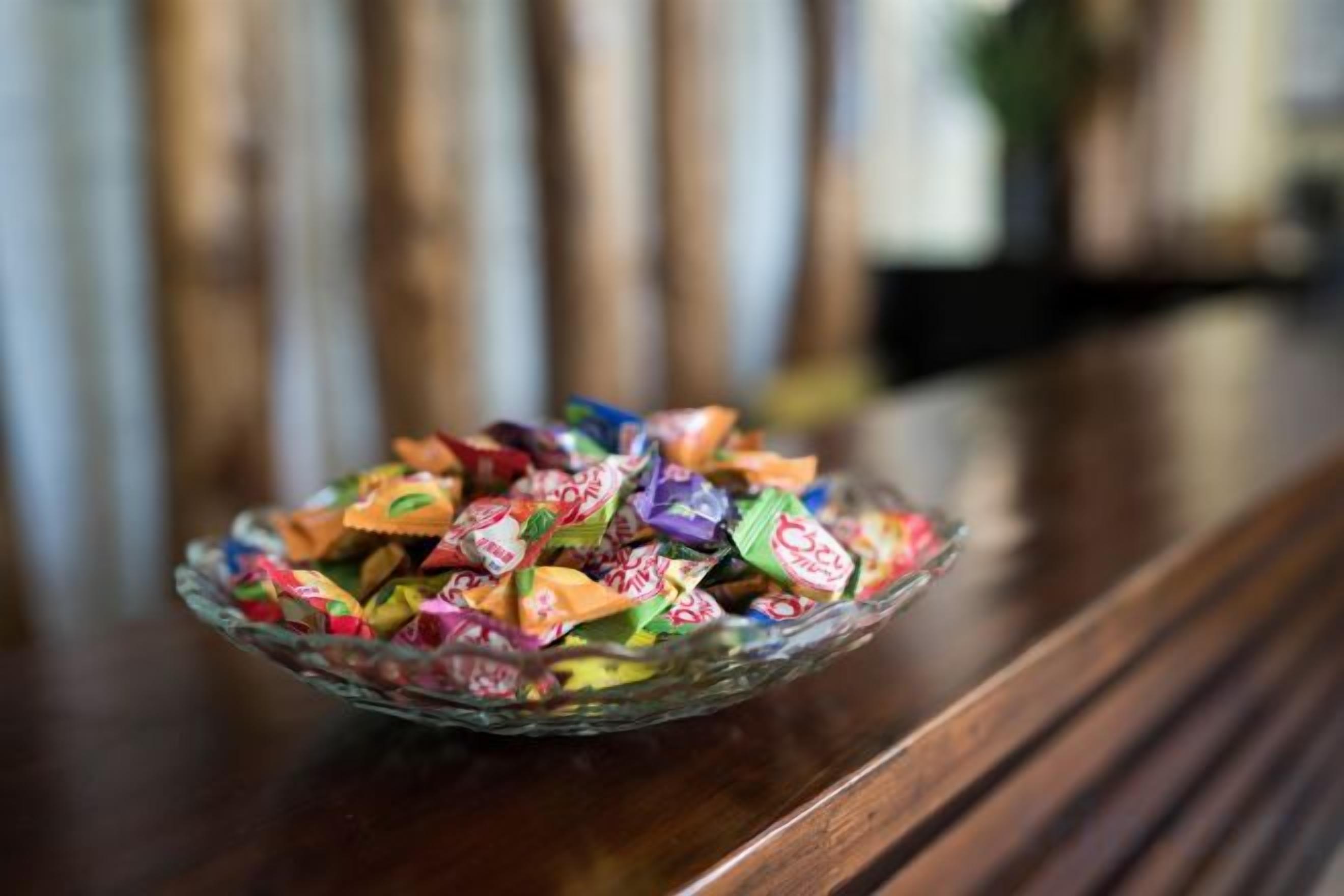 Un saladier en verre rempli d’un assortiment de bonbons, posé sur une surface en bois.
