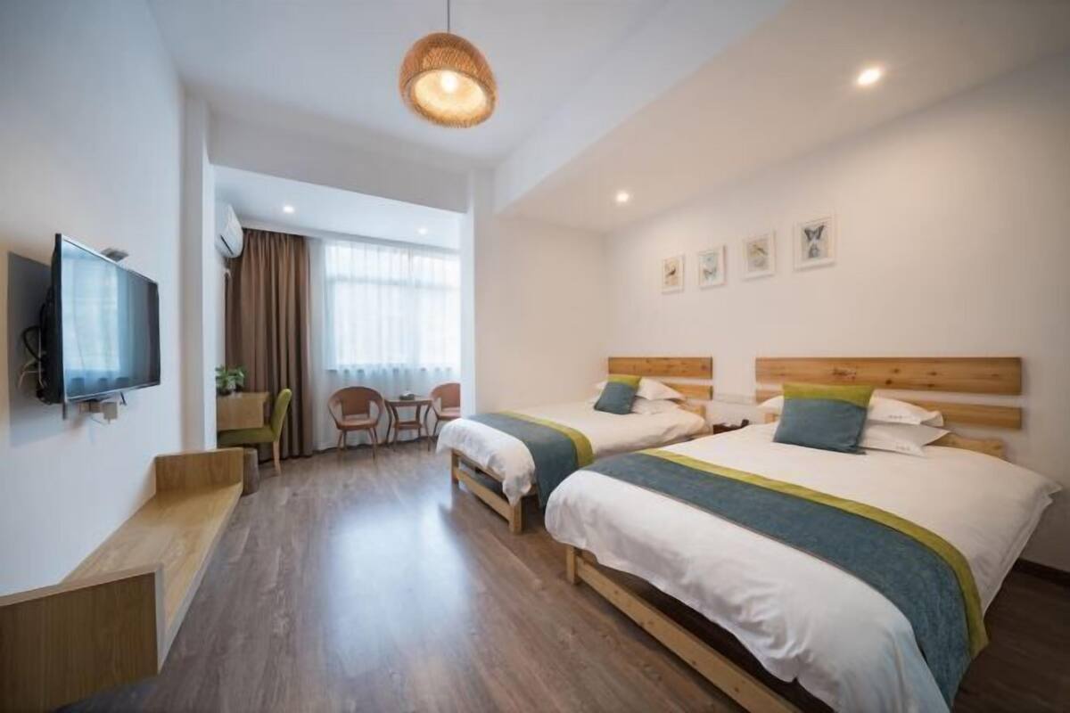 Habitación de hotel con dos camas, televisor, escritorio y una silla.