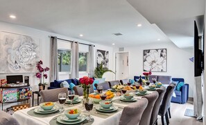 A dining area with a long table set for a meal, surrounded by sofas and chairs. - Heated Pool~Stellar stay in 7BD villa~Playground (Fort Lauderdale)
