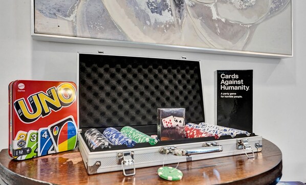A display of UNO cards, a deck of playing cards, and a box labeled "Cards Against Humanity" on a wooden table. - Heated Pool~Stellar stay in 7BD villa~Playground (Fort Lauderdale)