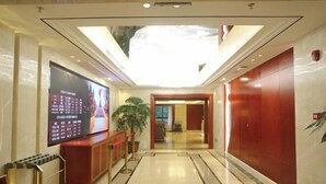 A hotel lobby with a large digital display, a reception desk, and a red wall. - Jiu'an Hotel (Jinggangshan City)