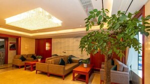 A modern hotel lobby with a large chandelier, comfortable seating, and a large indoor plant. - Jiu'an Hotel (Jinggangshan City)