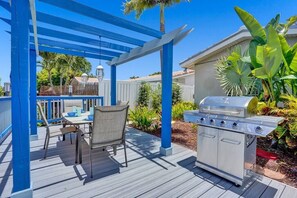 A patio with a grill, outdoor seating, and a pergola.