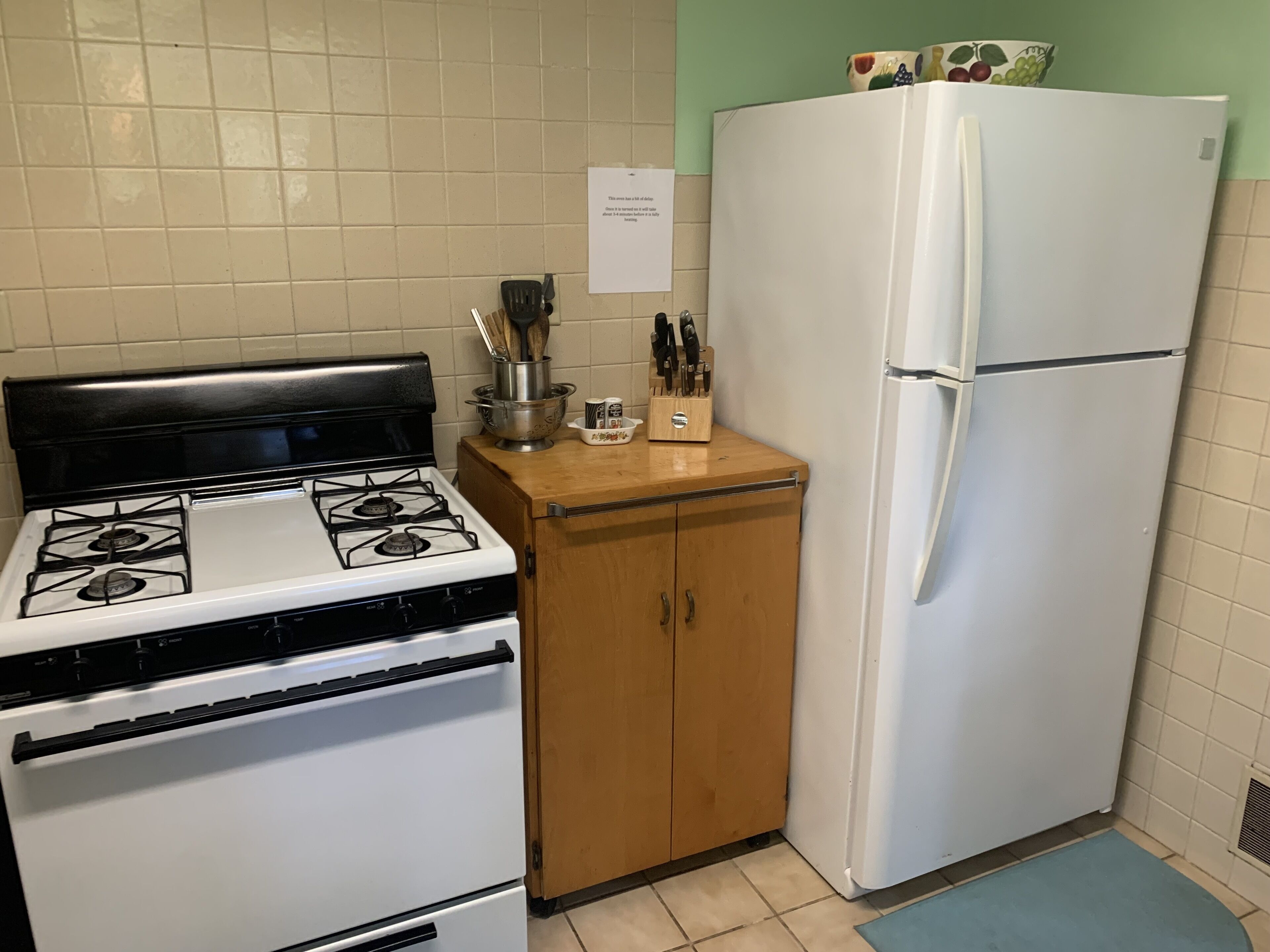 A kitchen with a white stove, wooden cabinets, and a white refrigerator.