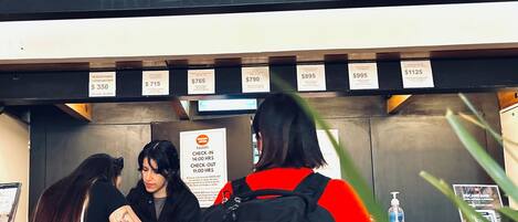 A hotel reception area with a sign reading "mundo joven" and room rates displayed.