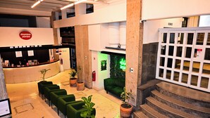 A lobby with a reception desk, green sofas, potted plants, and a staircase. - Hostel Mundo Joven (Mexico City)