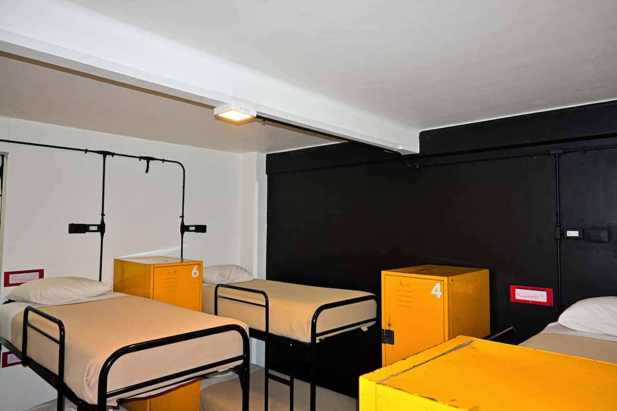 Ein Schlafsaalzimmer mit Etagenbetten, Schließfächern und einer schwarzen Wand.