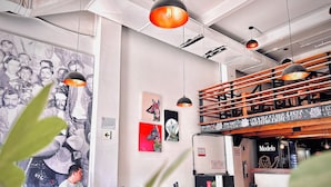 A café interior with a mural, wooden seating, and hanging pendant lights. - Hostel Mundo Joven (Mexico City)
