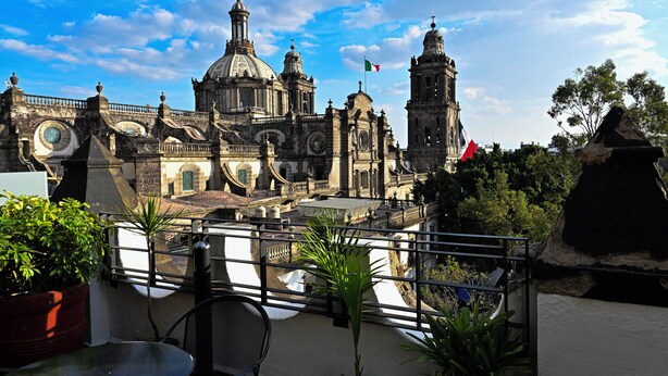 A historic building with domes and towers, surrounded by greenery and a clear sky. - Hostel Mundo Joven (Mexico City)
