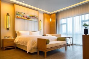 Ein Hotelzimmer mit Bett, Nachttischen, einer Couch, einem Gemälde und einem Fenster mit Vorhängen.