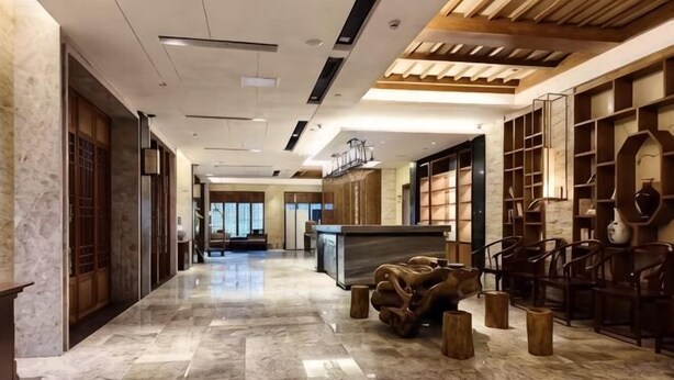 Un hall de hotel con piso de mármol, mobiliario de madera y una recepción.