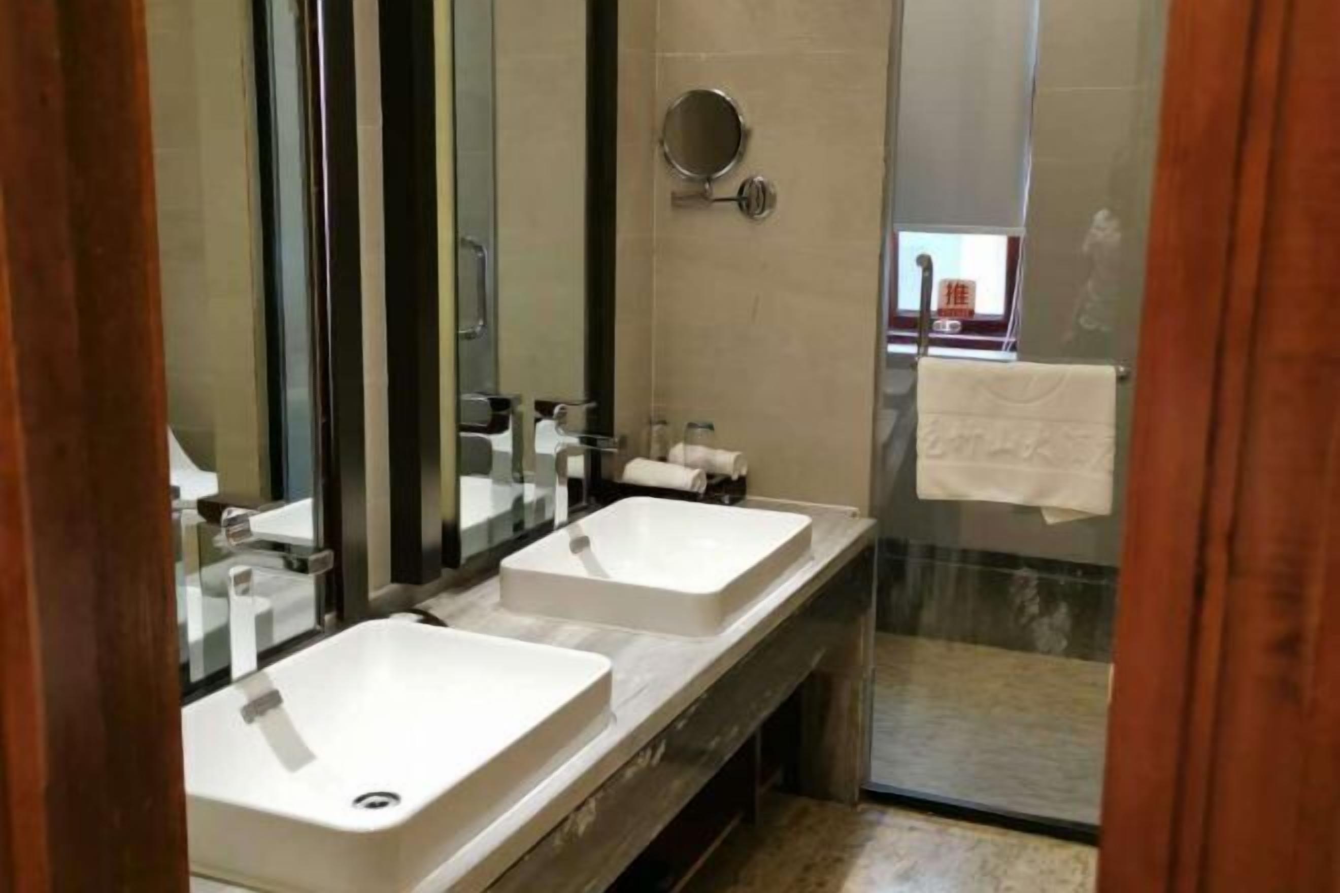A modern bathroom with two sinks, a large mirror, and a glass shower enclosure.