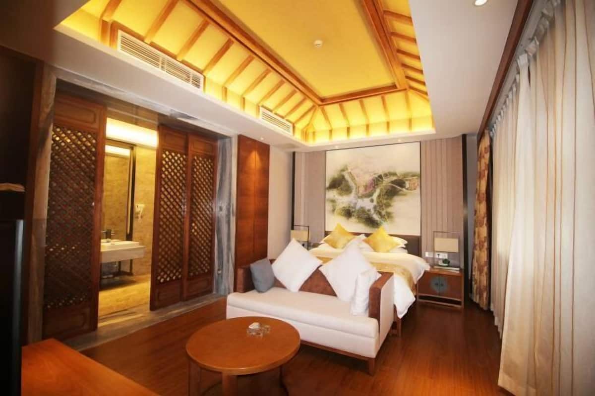 Une chambre d’hôtel avec un plafond en bois, un canapé, une table ronde et un lit avec des oreillers.