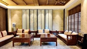 Un salón comedor de estilo tradicional con un sofá, mesas auxiliares y un biombo decorativo.