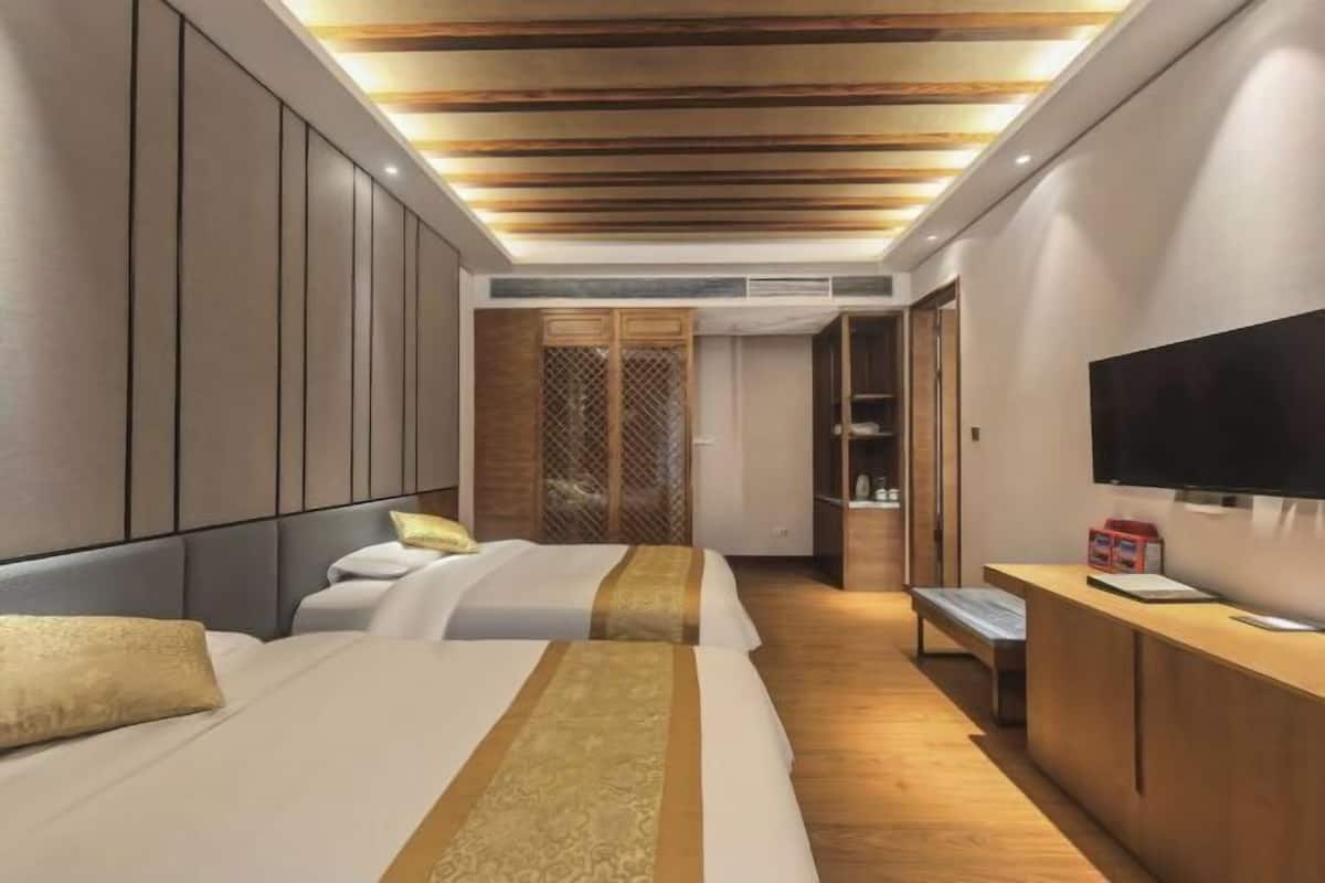 Une chambre d’hôtel moderne dotée d’un grand lit, d’une télévision, d’un bureau en bois et d’un dressing.