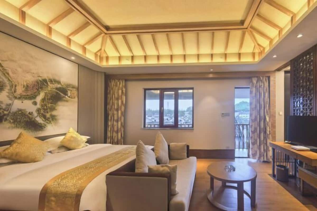Une chambre d’hôtel avec un lit, un canapé, une télévision et une vue sur la ville.