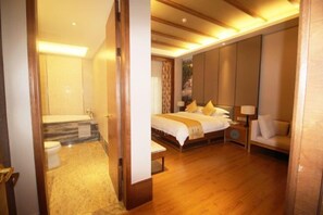 A spacious hotel room with a large bed, a sitting area, and a separate bathroom.