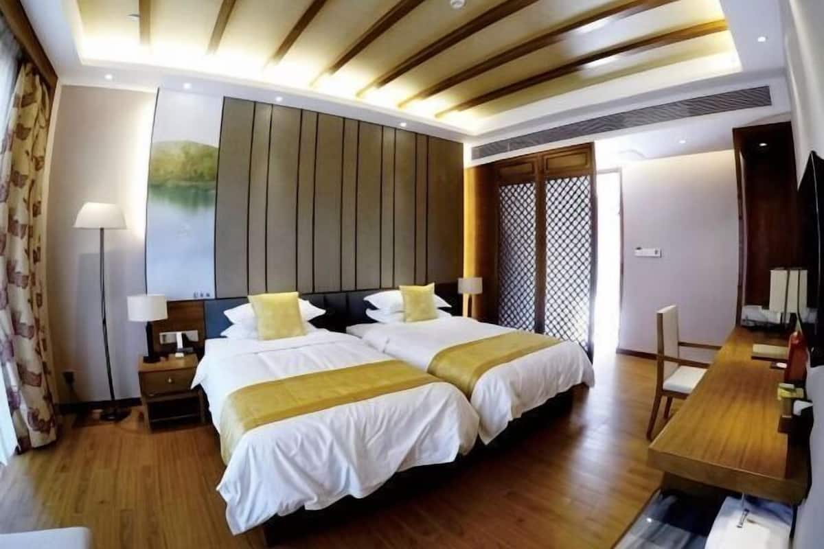 Une chambre d’hôtel avec deux lits, un plafond en bois, un bureau et une vue sur l’extérieur.