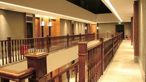 Un pasillo de hotel con barandillas de madera, suelo de mármol e iluminación empotrada.