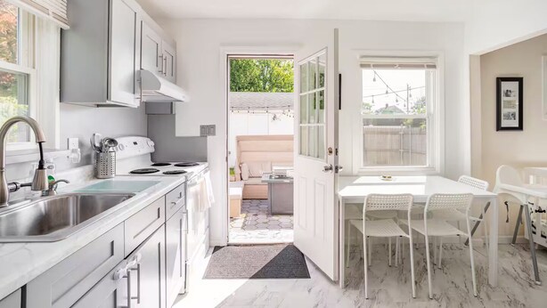 Une cuisine moderne avec un coin repas, une vue sur le jardin et un intérieur blanc.