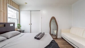 Une chambre à coucher avec un lit, un miroir, un canapé et une armoire.