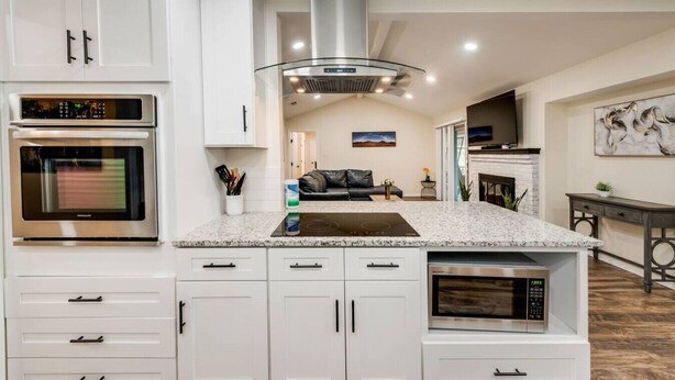 Een moderne keuken met witte kasten, roestvrijstalen apparatuur en een centraal eiland.