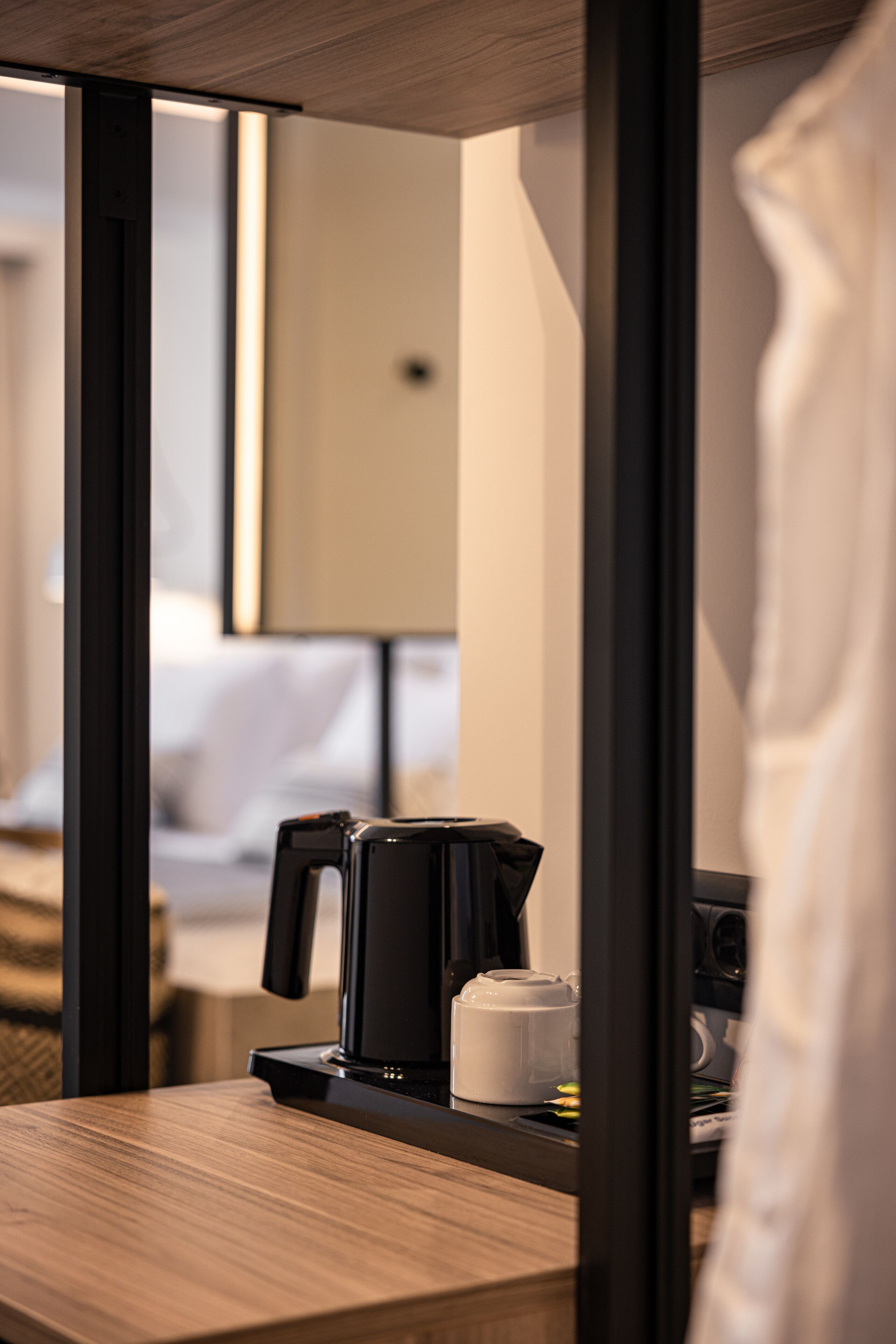 Une chambre d’hôtel avec une table en bois, une machine à café et une tasse blanche.