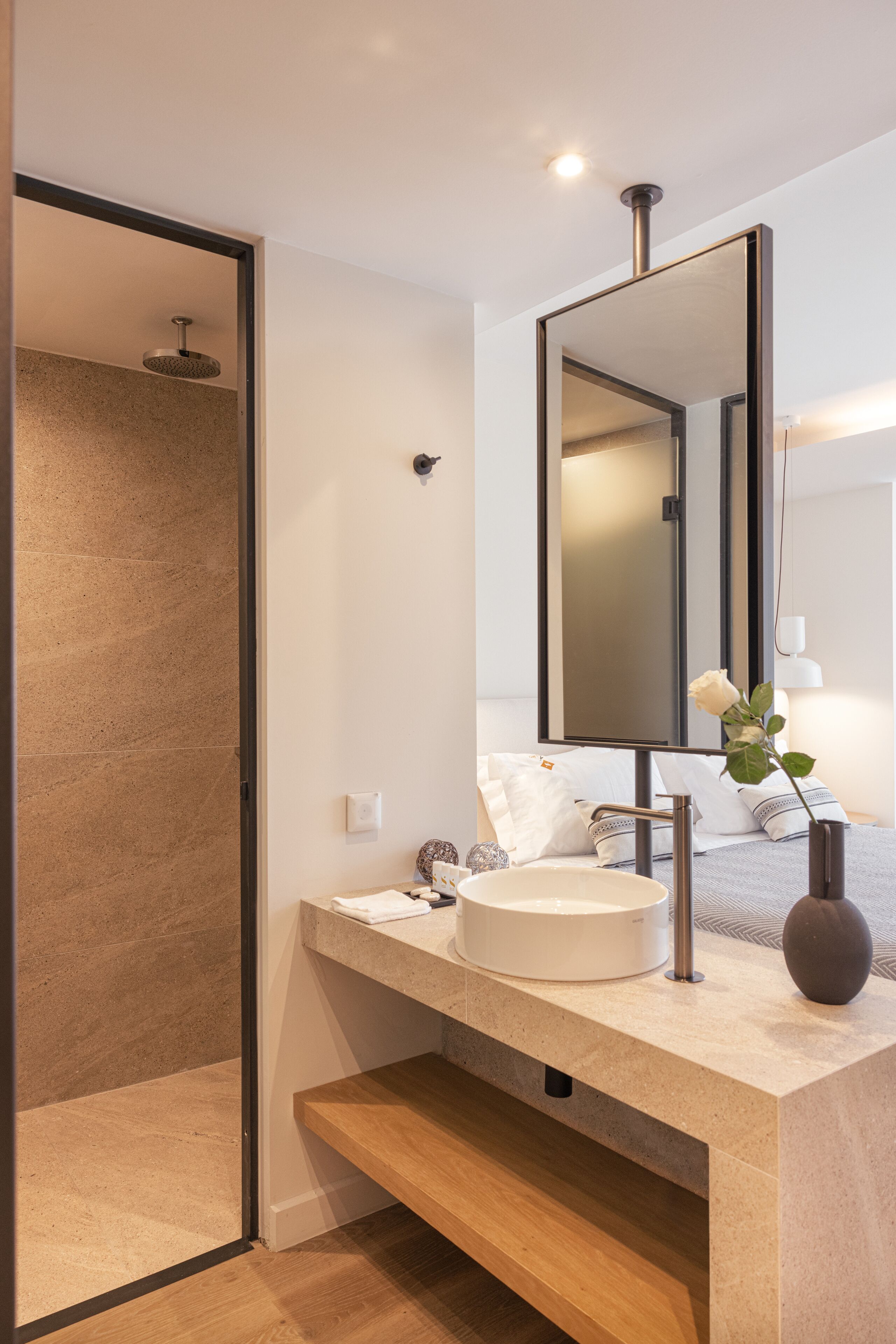 A modern bathroom with a large mirror, a round sink, and a shower area.