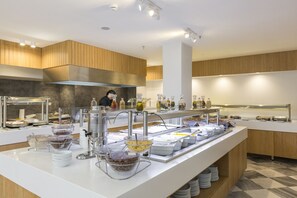 A buffet setup with various food stations, including a salad bar, hot and cold beverage dispensers, and a beverage station with a variety of drinks. - Erato by Samian Mare (Samos)