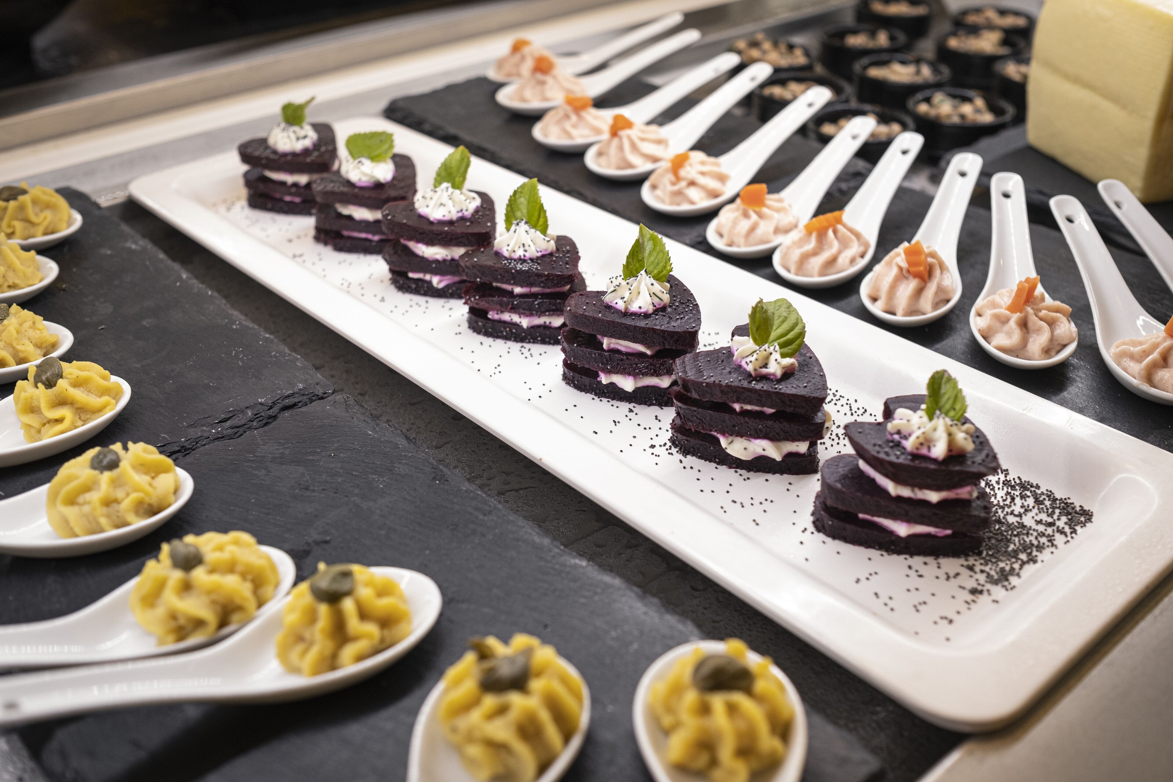 Diversos postres dispuestos sobre un plato blanco rectangular, junto con cucharas blancas individuales.