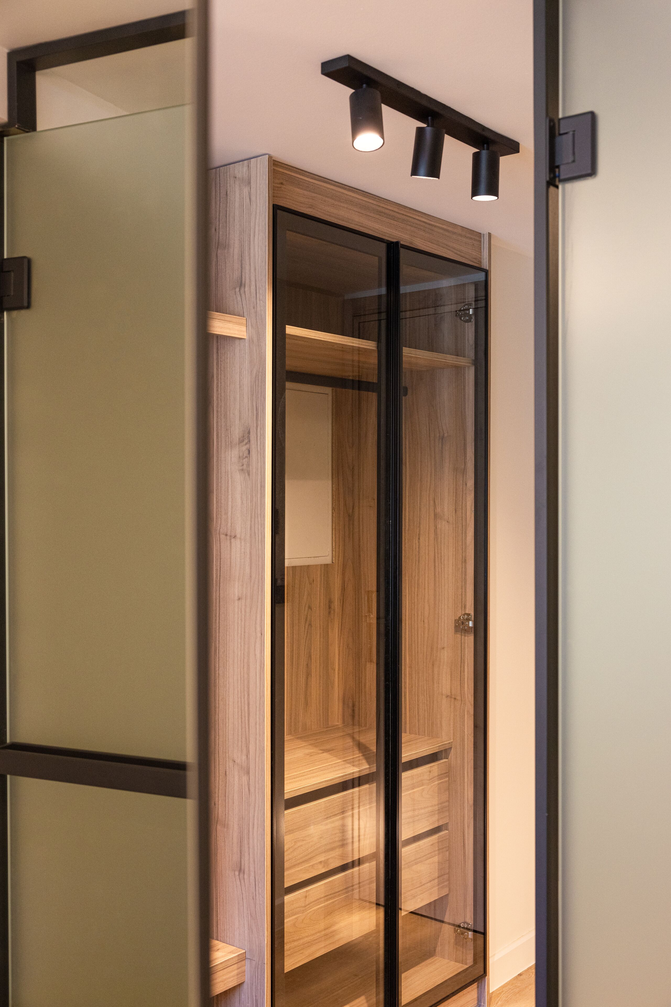 A modern closet with sliding doors, built-in shelves, and a track lighting system.