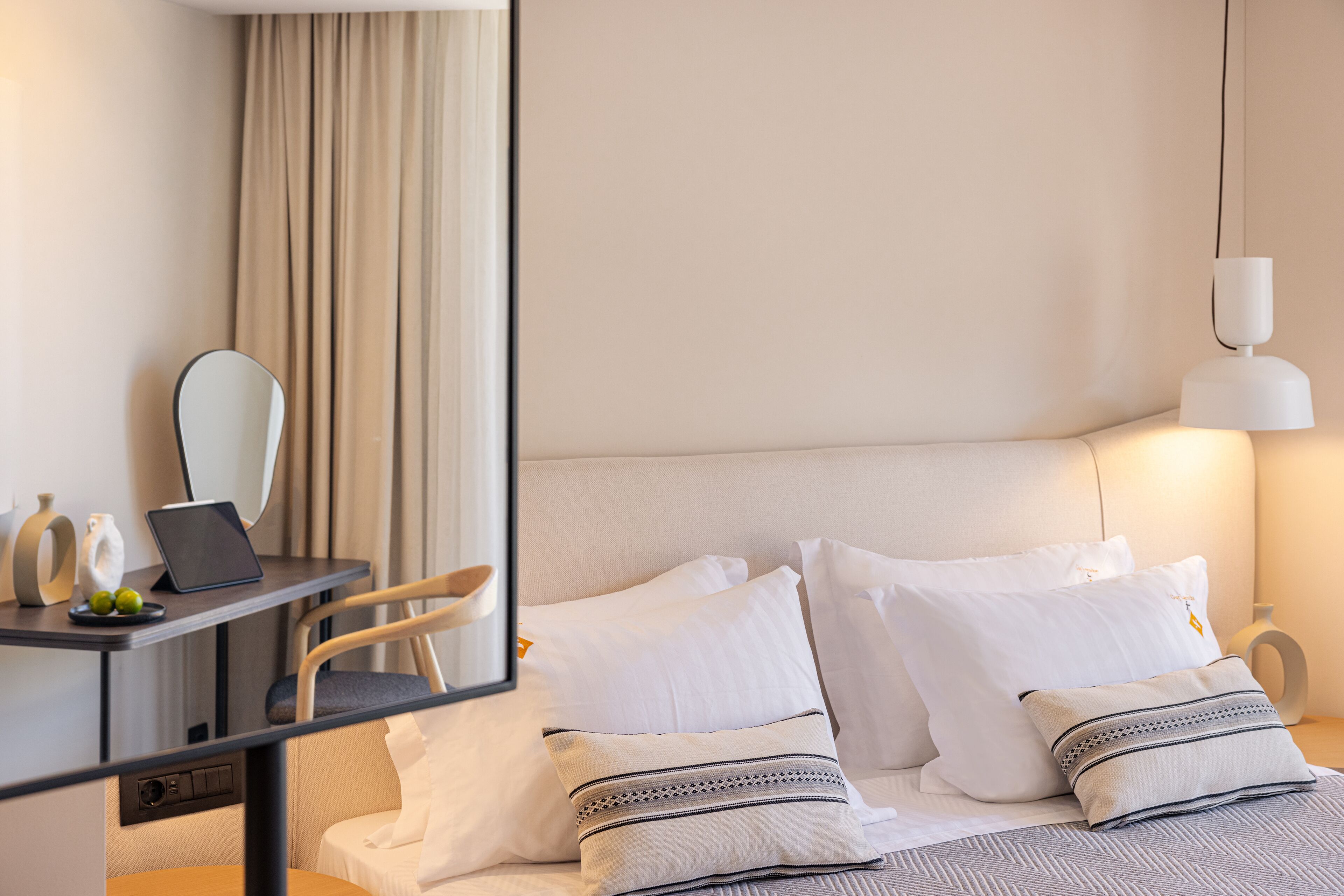 Ein Hotelzimmer mit einem Bett, einem Schreibtisch mit einem Laptop, einem Stuhl und einem Nachttisch mit einer Lampe.