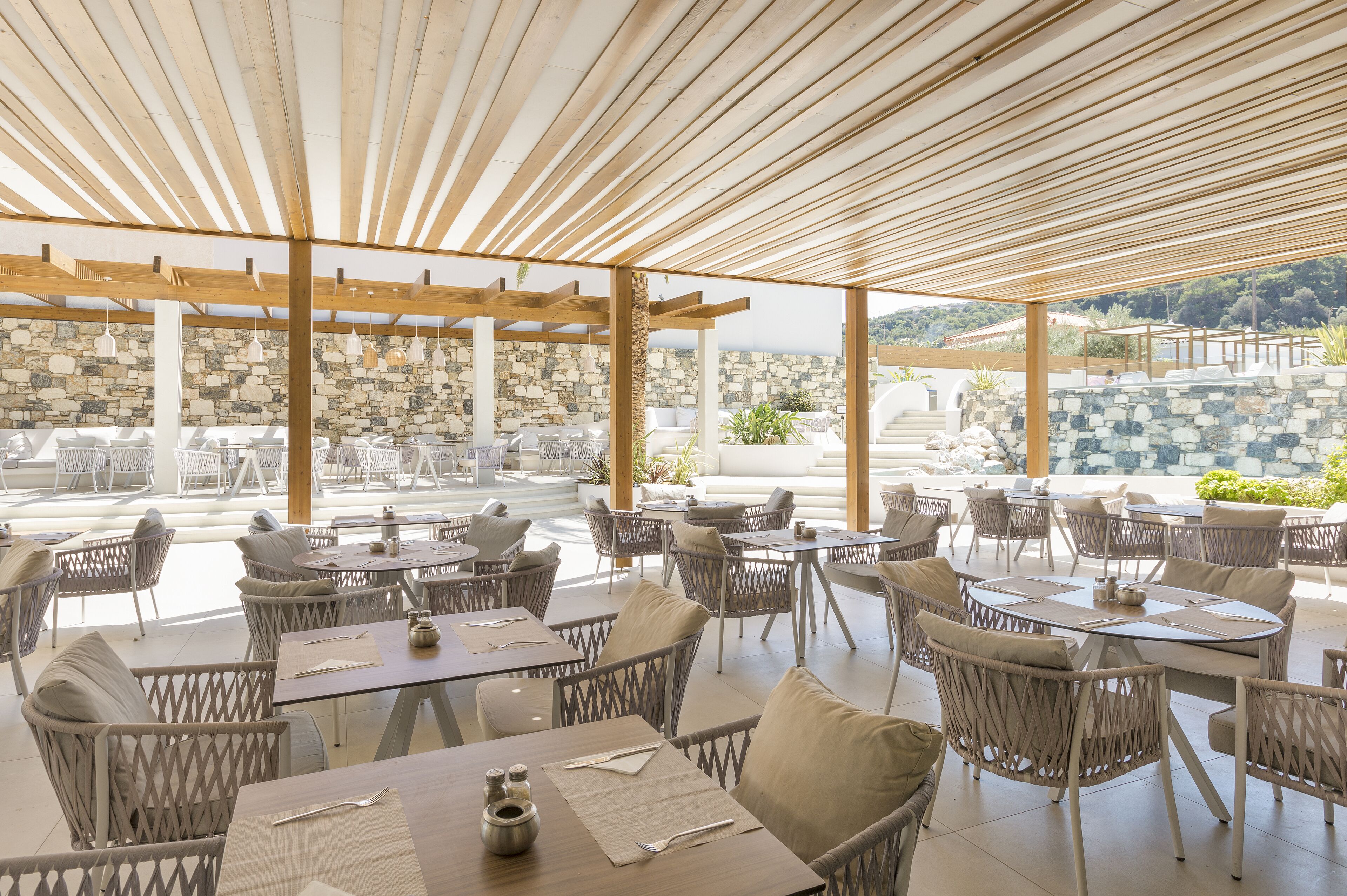 An outdoor dining area with wicker furniture and stone walls.