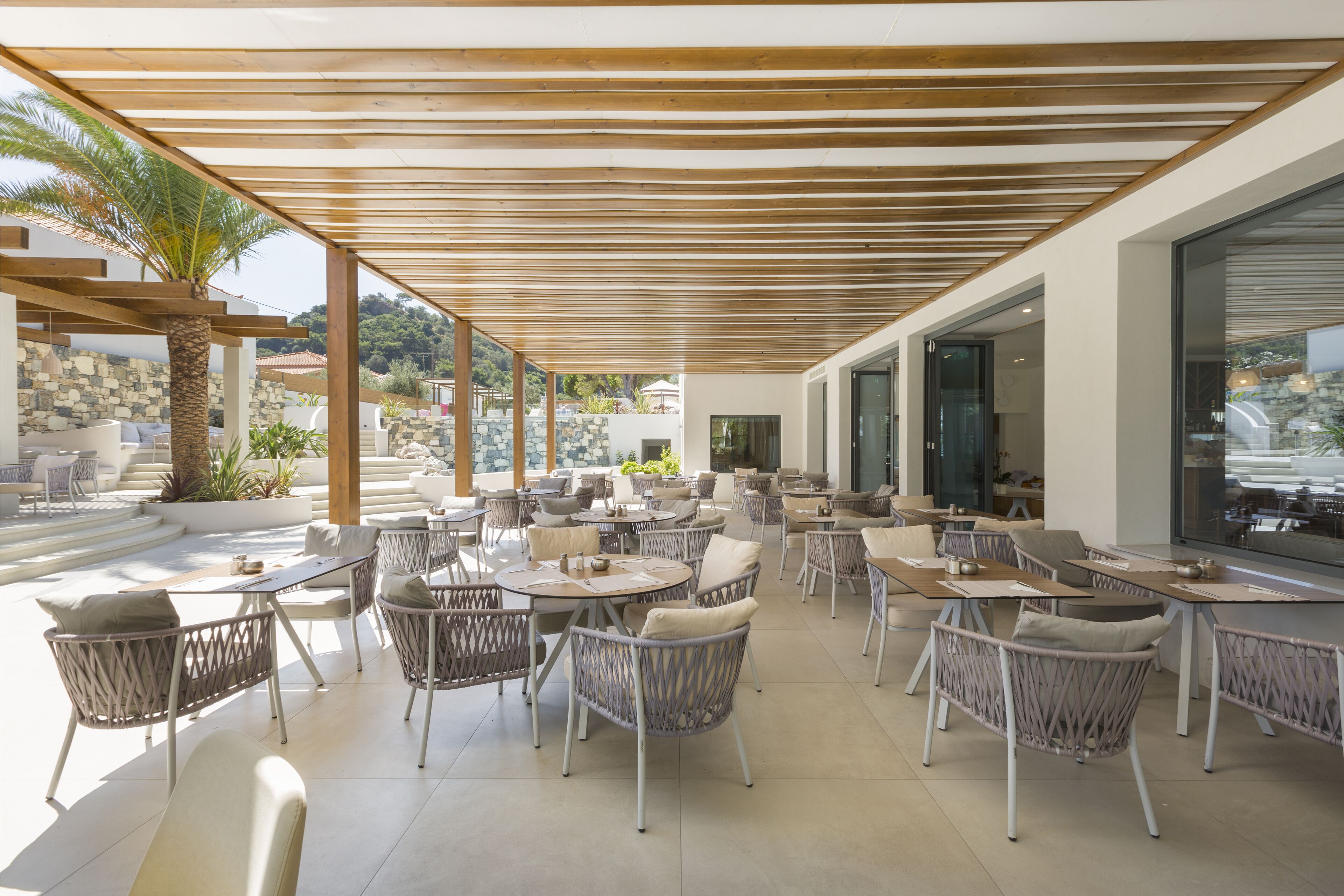 An outdoor patio area with wicker furniture and a wooden pergola.